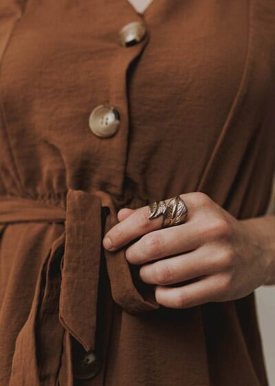 lose-up of a woman's hand with rings resting on brown suede fabric, representing calm and presence