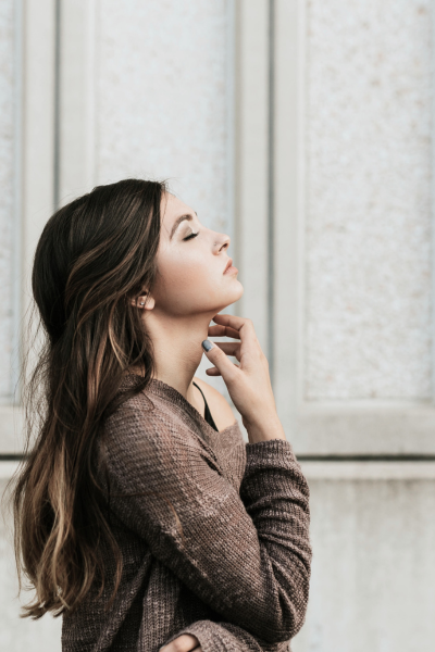 A woman with long dark hair, face tilted upward in a quiet moment of stillness and reflection after hypnotherapy for anxiety