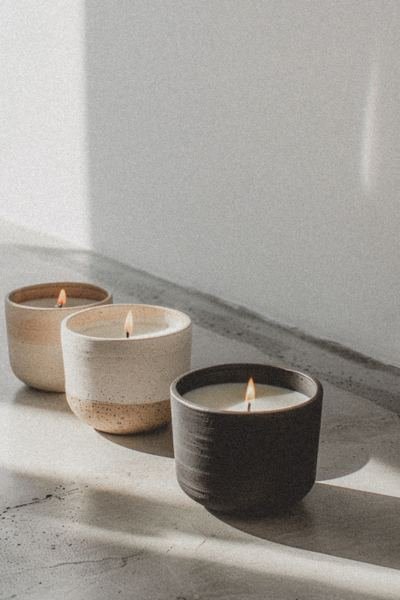 Three lit candles in ceramic holders on a marble surface, representing warmth, calm and a safe space for hypnotherapy in Tamworth