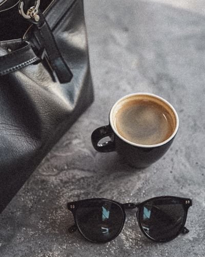 Coffee mug and sunglasses on a dark surface, representing a quiet moment of pause