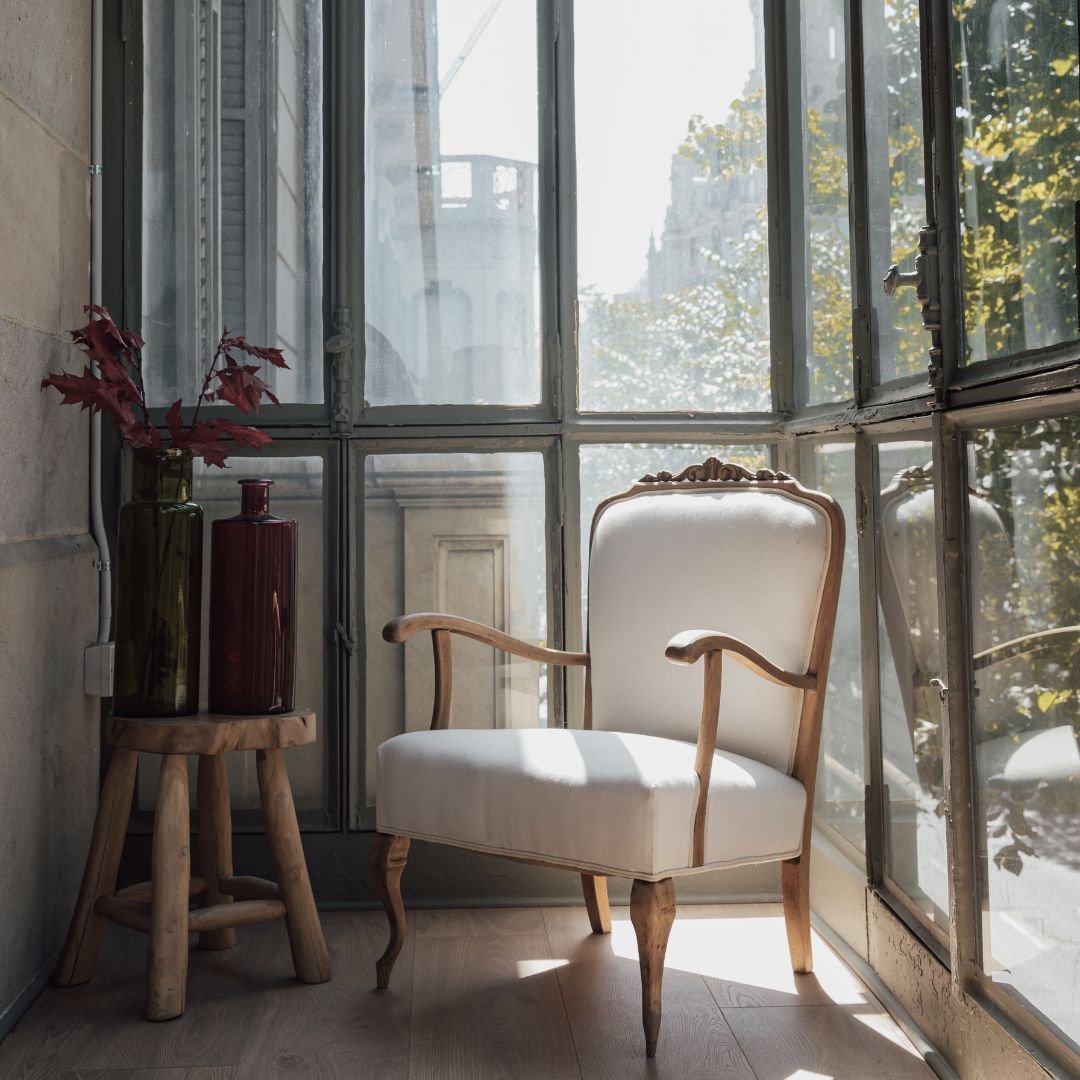 Elegant white armchair in soft natural light beside large French windows, representing a calm and welcoming hypnotherapy space in Tamworth, Staffordshire