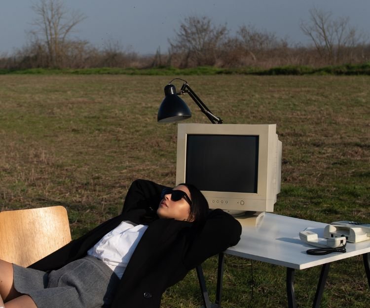 Woman relaxing beside an old computer monitor in a field