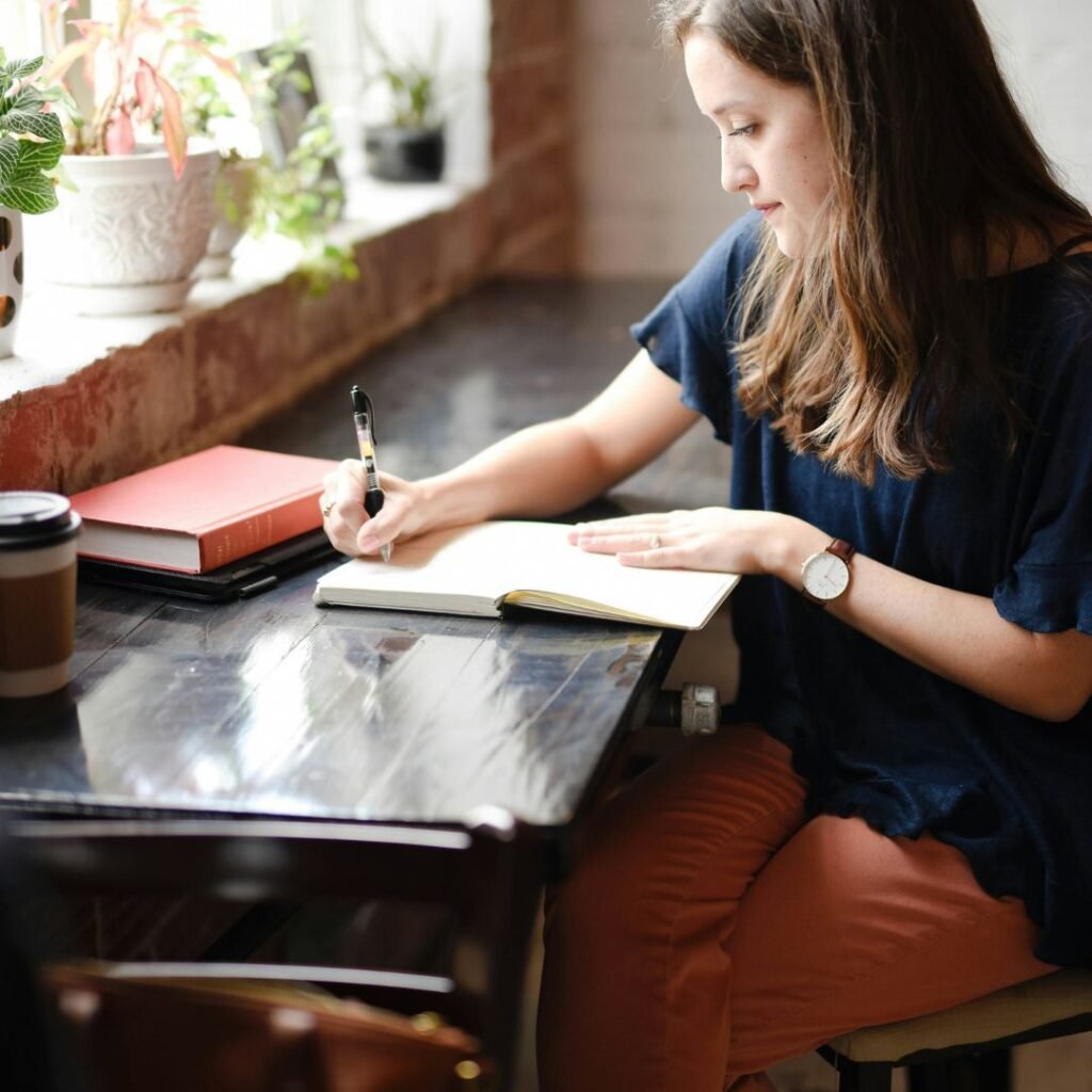 Woman journalling at a cafe, reflecting on stress and rest