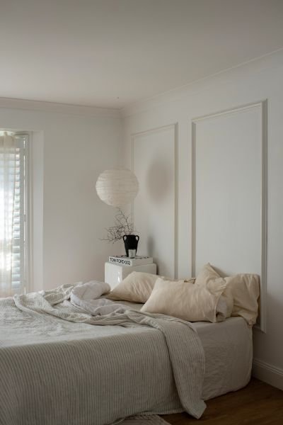 serene minimalist bedroom with soft linen and a round paper pendant light image representing hypnosis work for insomnia