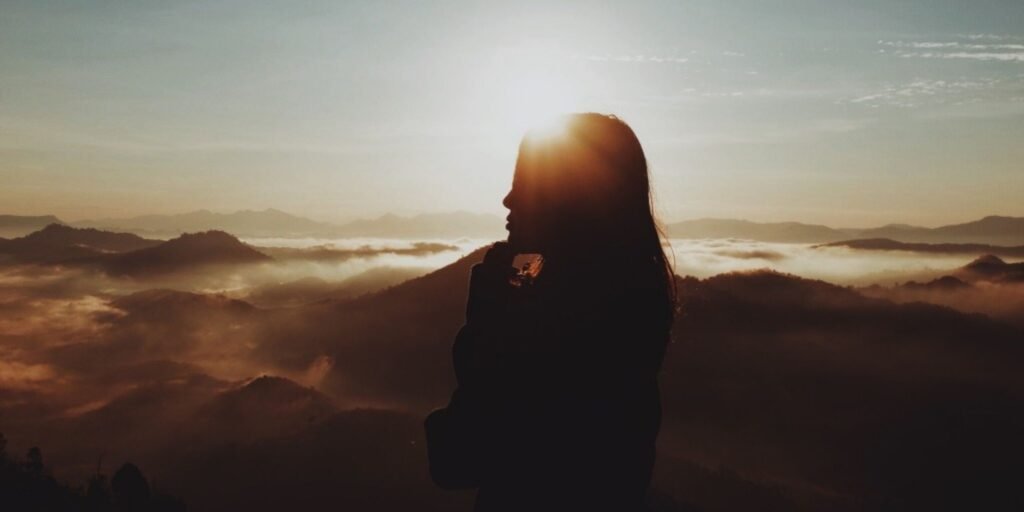 Person silhouetted at sunrise representing personal growth and reflection