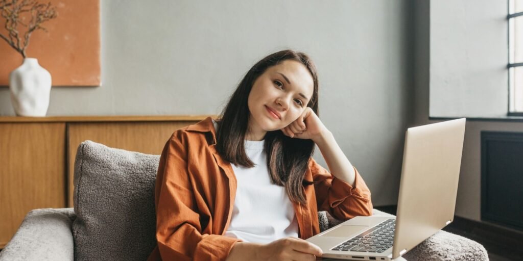 Woman smiling at laptop during online personal development session