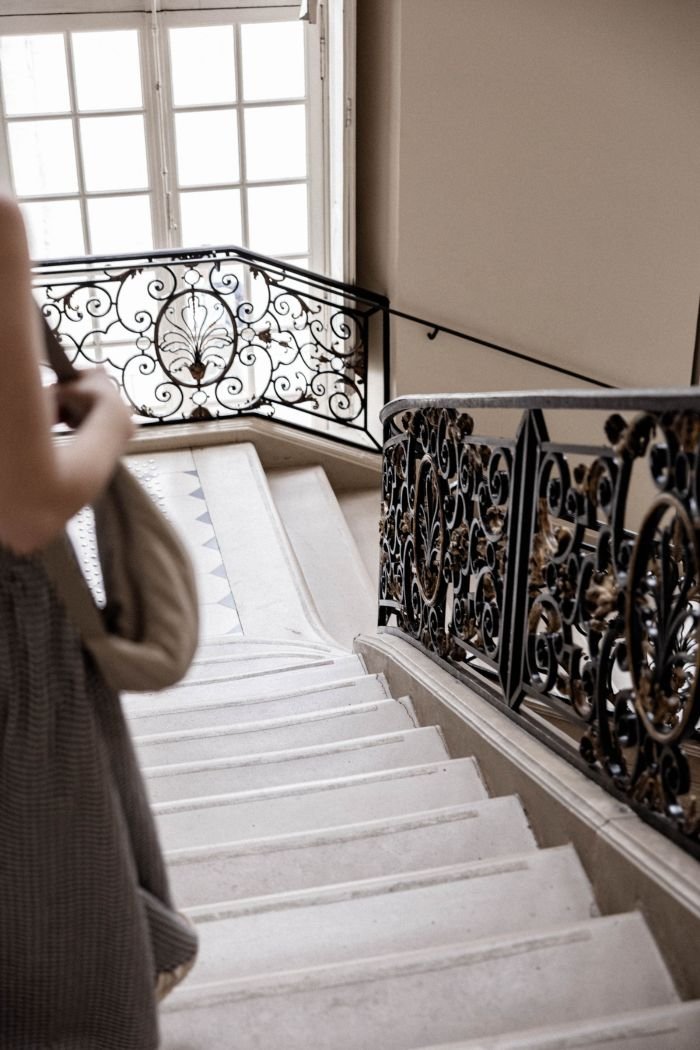 An ornate iron staircase railing in a softly lit interior, evoking the slow, considered steps of recovery