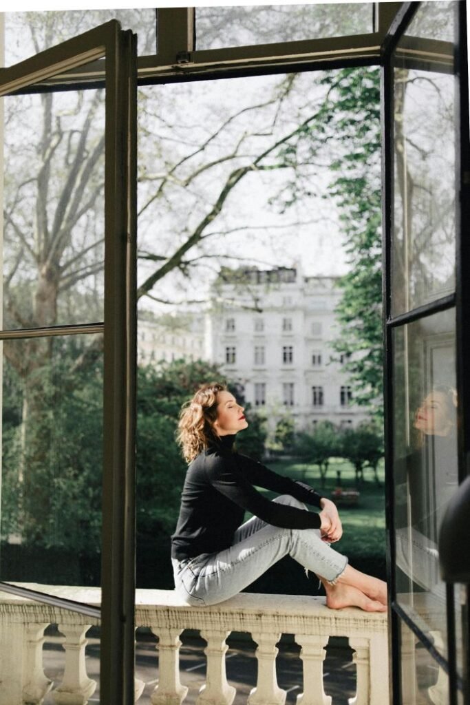Woman with dark hair sat on balcony on a spring day in the sunshine.