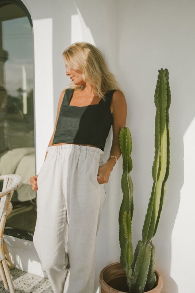 A woman in a black top and linen trousers standing at ease beside a tall cactus in warm sunlight reflecting calm after hypnotherapy for anxiety
