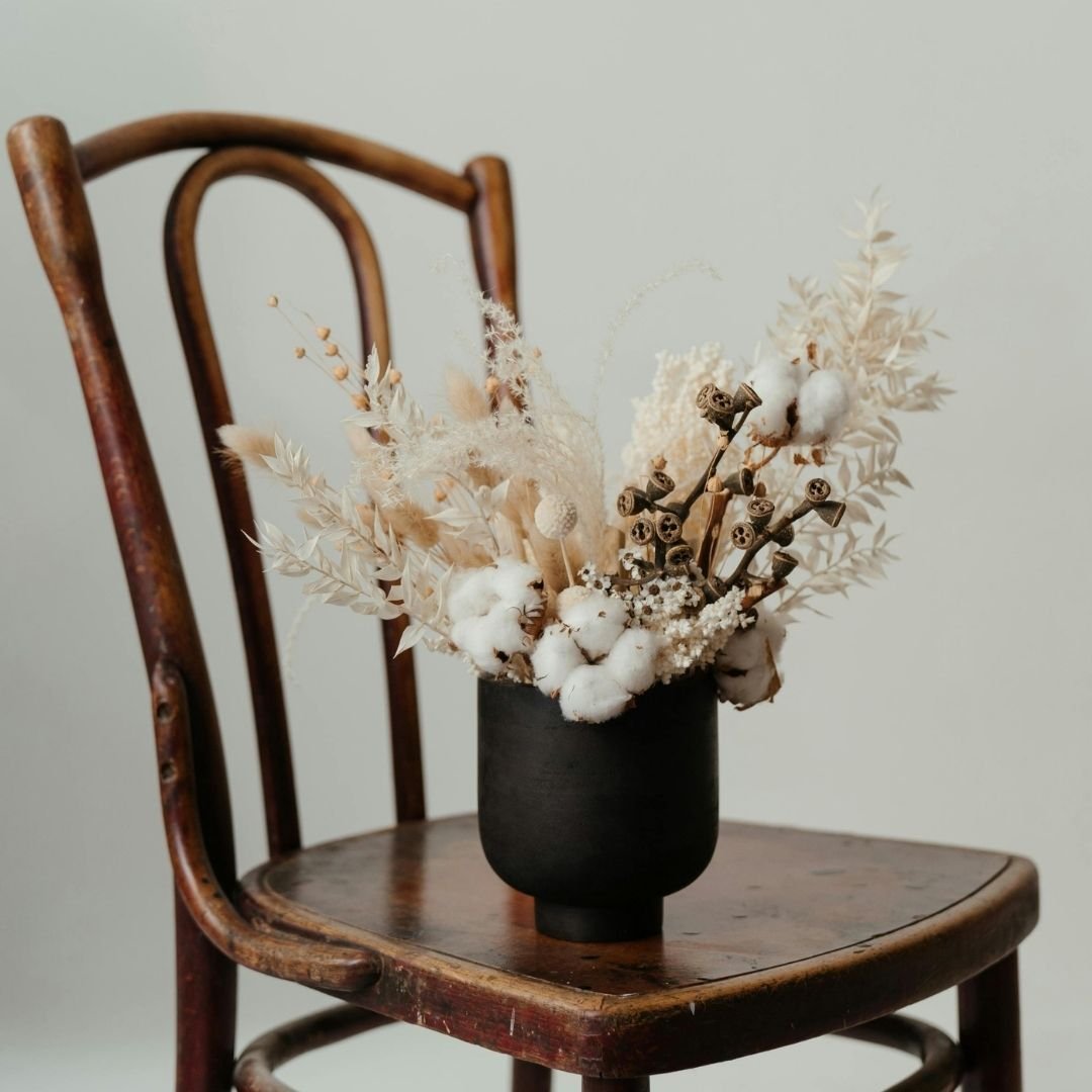 A warm interior with a chair and a dried flower arrangement in a glass vase, representing the calm, welcoming environment of in-person therapy sessions in North Warwickshire near Tamworth