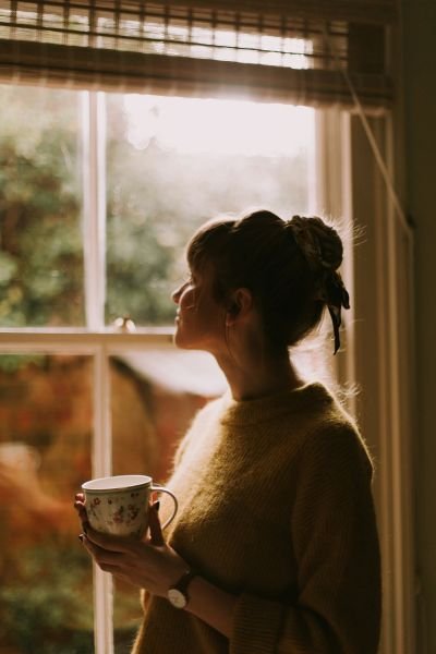 Woman sitting mindfully by a window, representing personal development and wellbeing