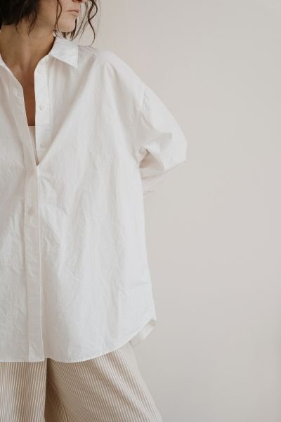 Woman in a linen shirt looking thoughtfully to the side, calm and grounded