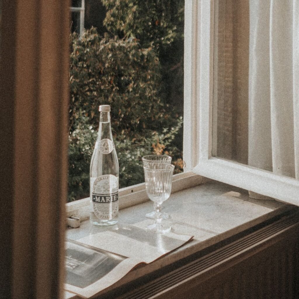 Glass of water on windowsill in natural light, calm bedroom setting