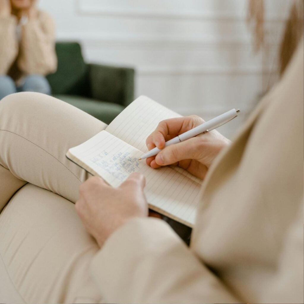Person writing notes in a notebook, representing the collaborative, personalised treatment planning approach used in therapy sessions in Warwickshire