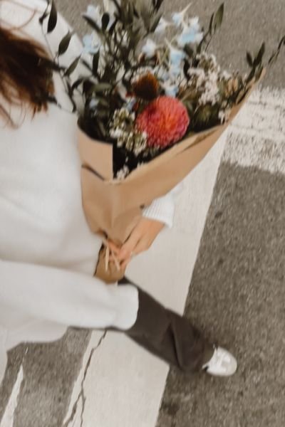 Woman in white holding a bunch of mixed flowers, representing the warmth and personal approach of integrative ACT therapy in Warwickshire