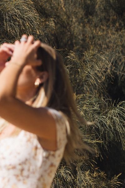 Woman in a sunlit field with her hand in her hair, representing relief and reconnecting with yourself after chronic stress